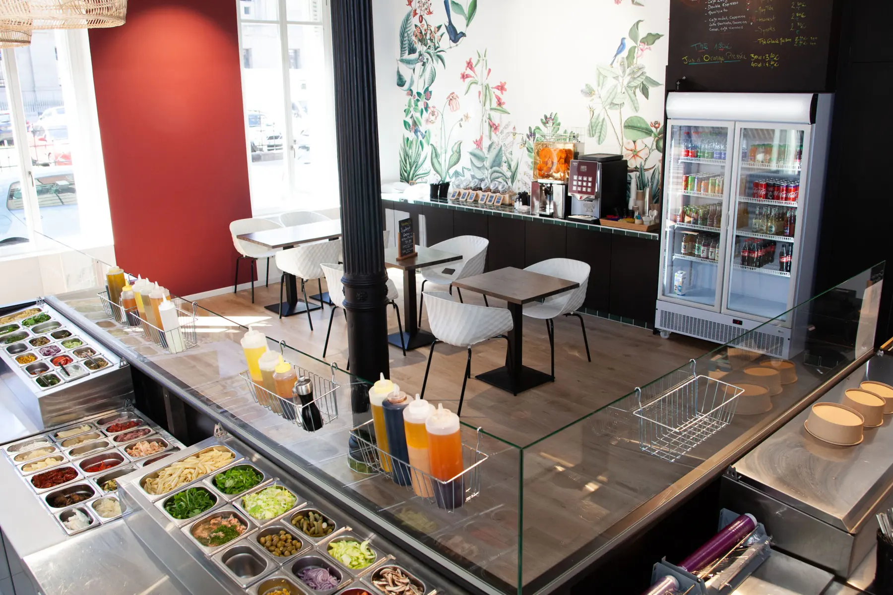 Le bar à salades : les bacs d'ingrédients frais devant le papier peint fleuri